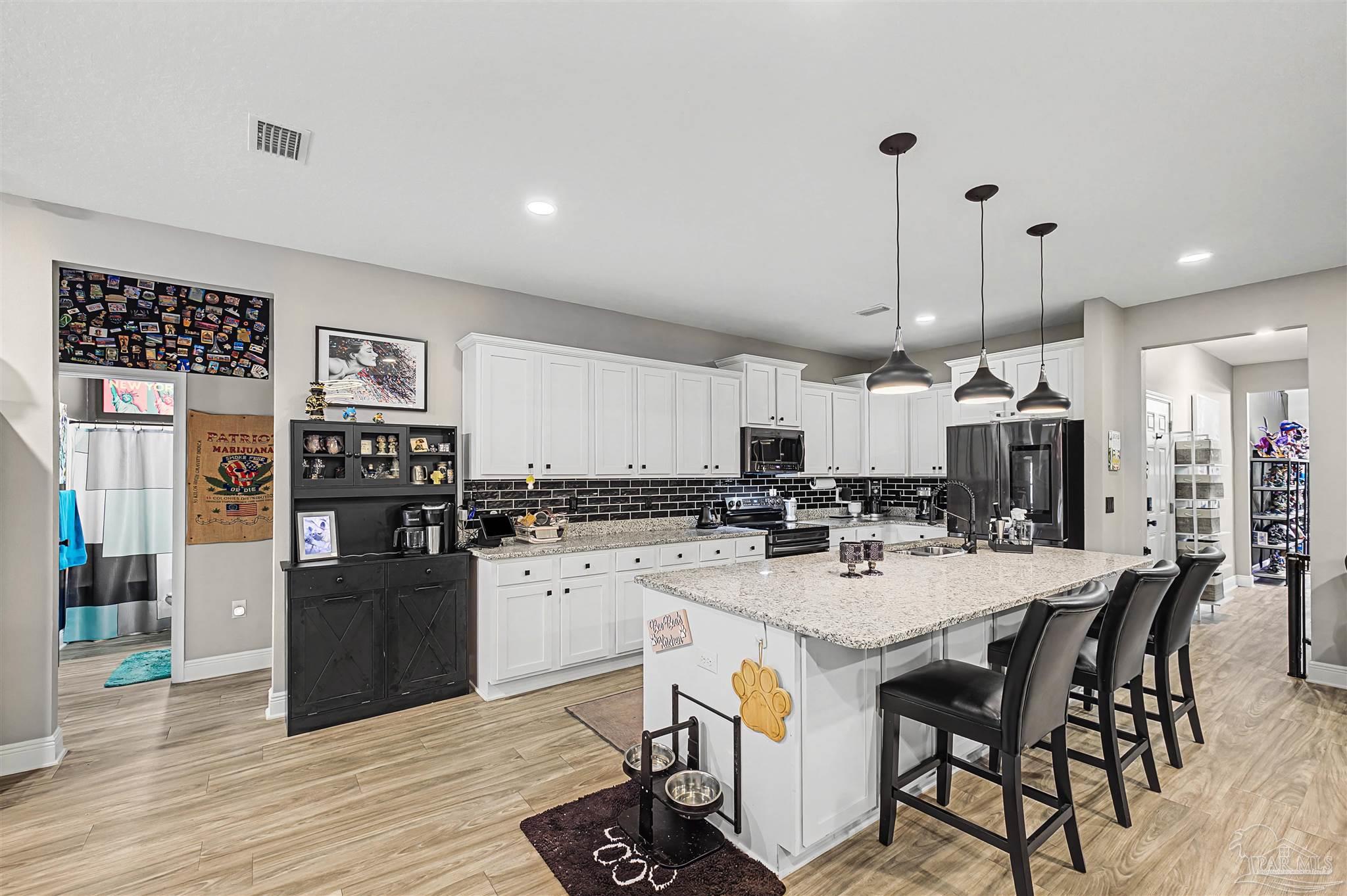 327 Cayden Way Cantonment, FL 32533 - Photo 6 of 64 a kitchen with stainless steel appliances kitchen island granite countertop a table chairs and a refrigerator