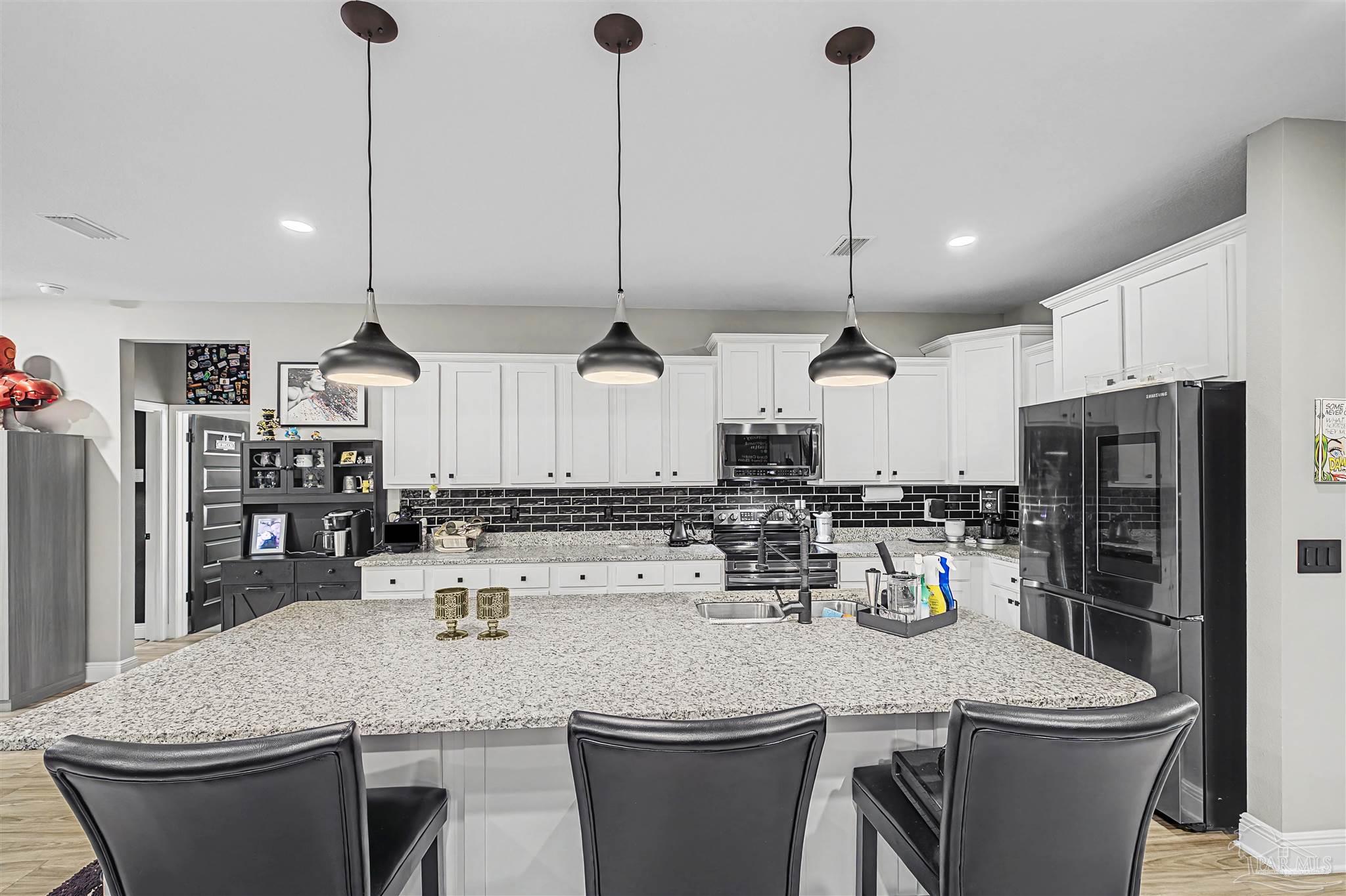 327 Cayden Way Cantonment, FL 32533 - Photo 10 of 64 a kitchen with sink a refrigerator and chairs