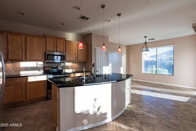 a kitchen with kitchen island granite countertop a sink stainless steel appliances and cabinets