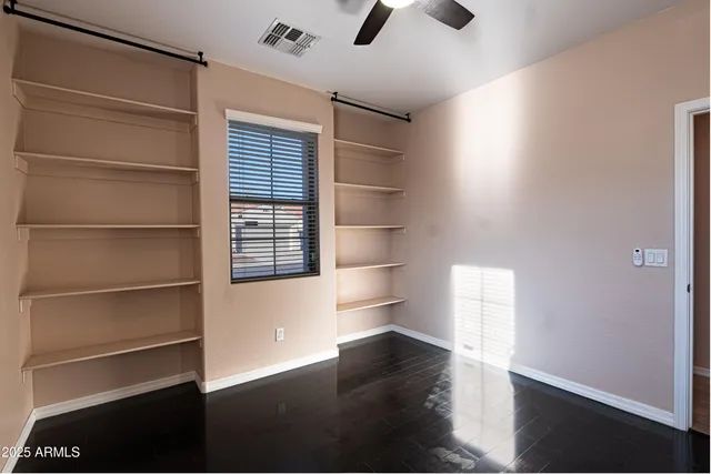 an empty room with wooden floor cabinet and windows