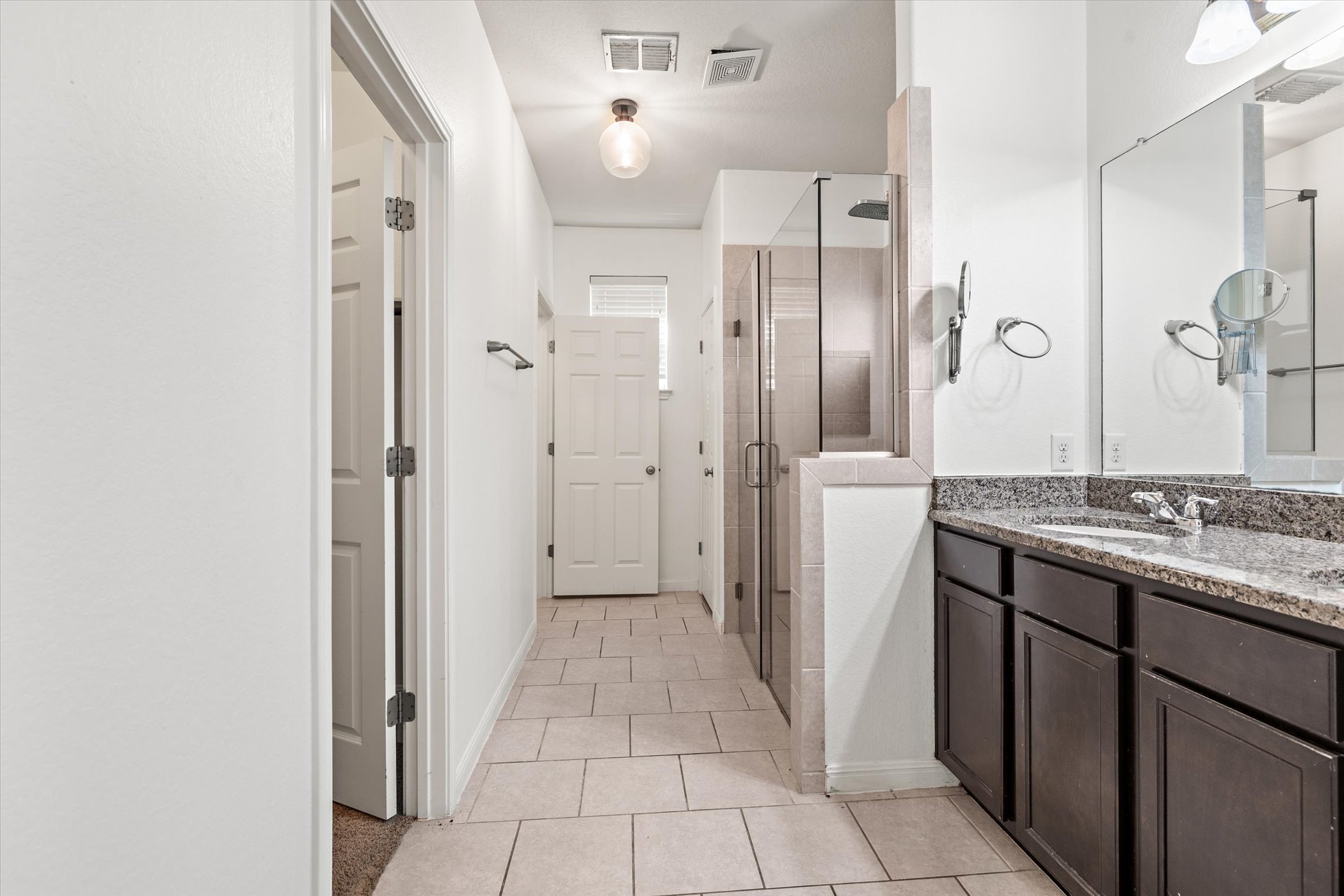7337 Menchaca Road, Unit #22 Austin, TX 78745 - Photo 10 of 25 Bathroom featuring a stall shower, double sink vanity, and light tile floors, with closets