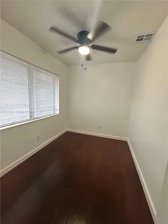 an empty room with a window and a fan