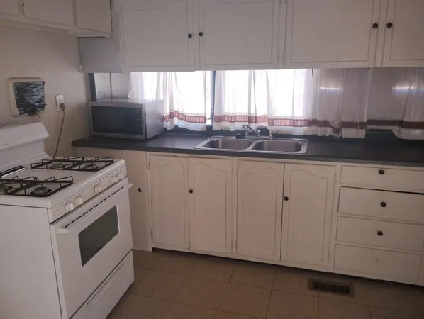 a kitchen with granite countertop white cabinets and white appliances