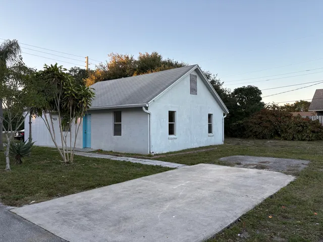 a view of a white house next to a yard and trees