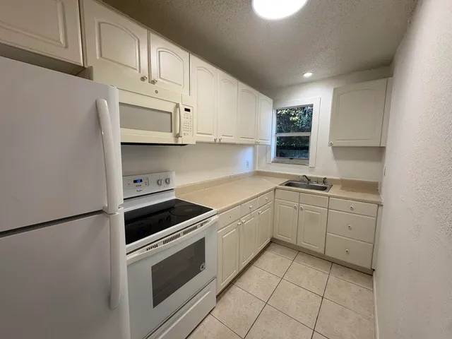 a kitchen with granite countertop white cabinets and appliances