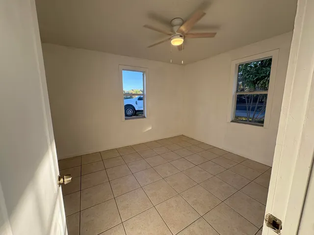 an empty room with windows and fan