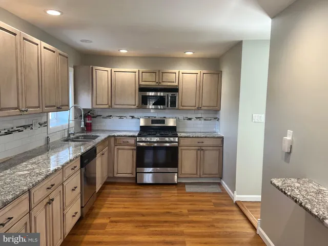 a kitchen with stainless steel appliances granite countertop a stove a sink and a refrigerator