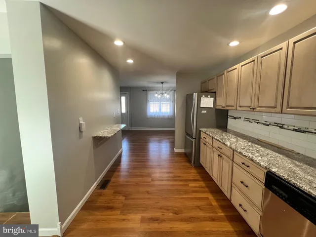 a large kitchen with granite countertop a sink and dishwasher a stove top oven with wooden floor