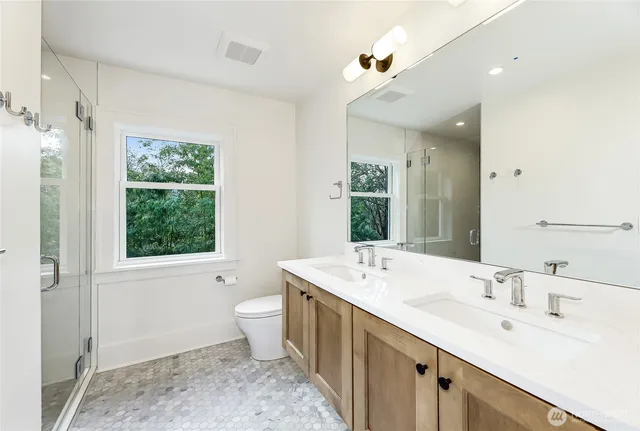 a spacious bathroom with a double vanity sink a large mirror and a toilet