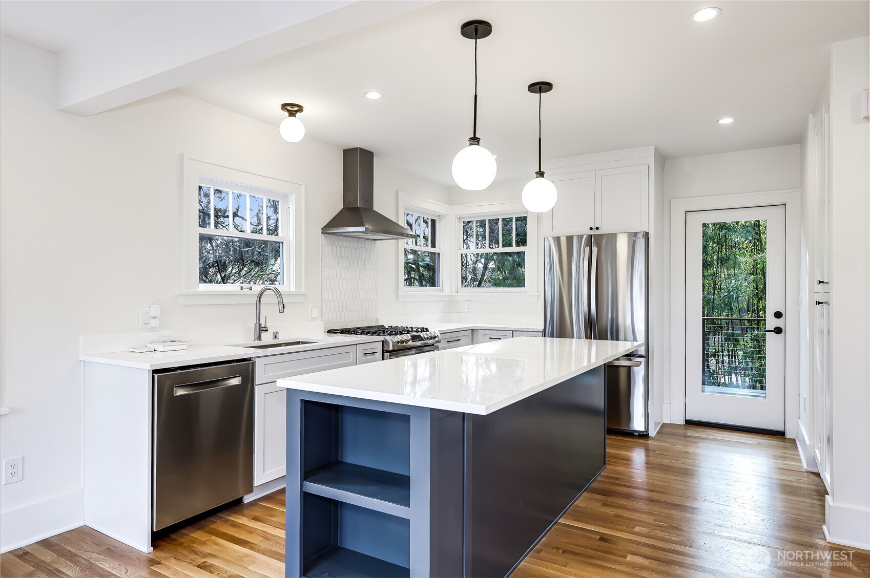 2207 East Republican Street Seattle, WA 98112 - Photo 3 of 24 a large kitchen with a stove a kitchen island a sink dishwasher a dining table and chairs with wooden floor