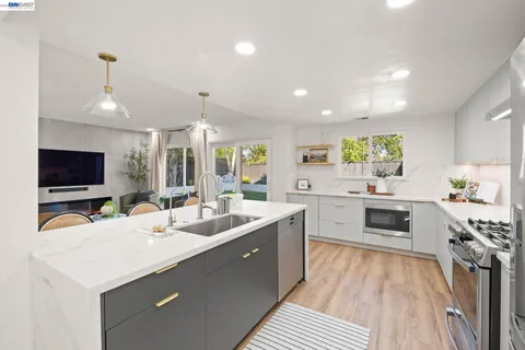 a large kitchen with sink a counter top space appliances and cabinets