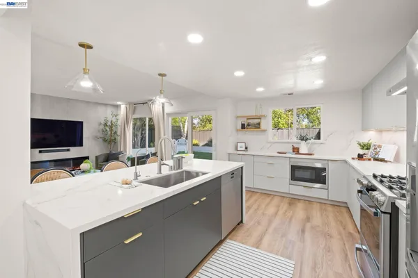 a large kitchen with sink a counter top space appliances and cabinets