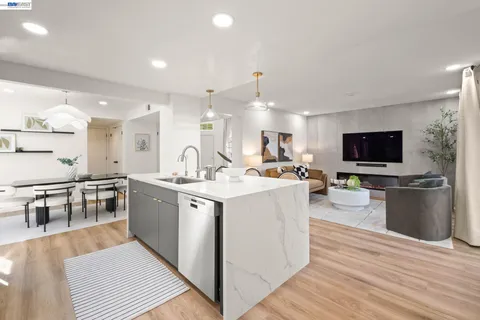 a large kitchen with stainless steel appliances a stove a sink dishwasher a microwave oven with white cabinets and wooden floor