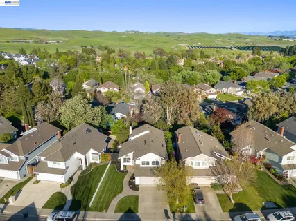 an aerial view of residential houses with outdoor space and trees