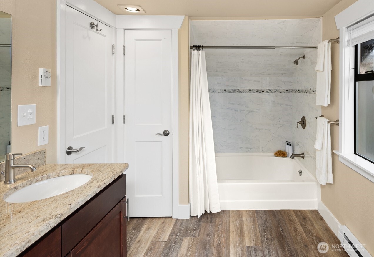 4522 3rd Avenue Northwest Seattle, WA 98107 - Photo 12 of 30 a bathroom with a granite countertop bathtub shower sink vanity and mirror