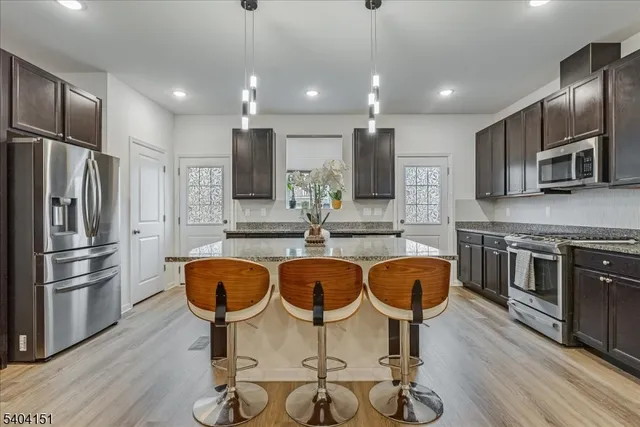 a kitchen with stainless steel appliances granite countertop a kitchen island a stove a refrigerator and a sink