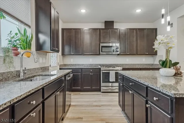 a kitchen with stainless steel appliances granite countertop a sink stove and cabinets