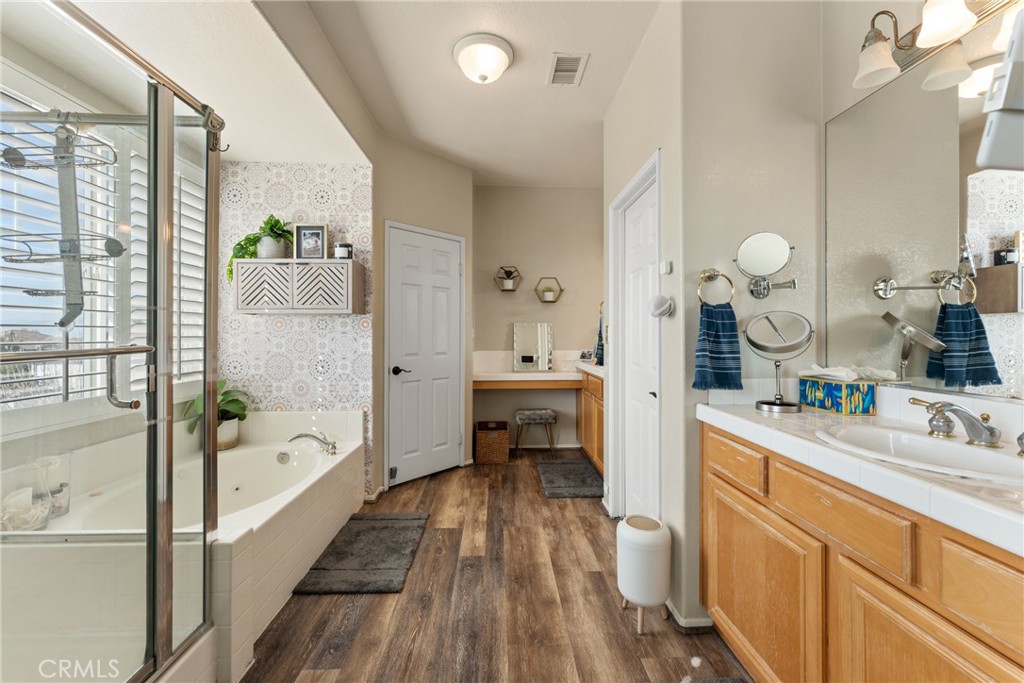 8553 Lodgepole Lane Riverside, CA 92508 - Photo 33 of 75 a spacious bathroom with a double vanity sink a mirror a bathtub and next to a window