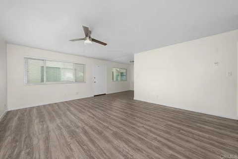 an empty room with wooden floor ceiling fan and windows