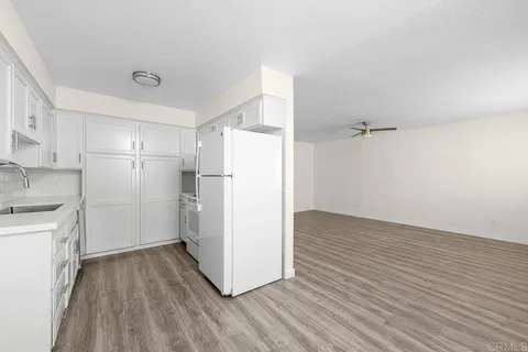 a view of a kitchen with a refrigerator a stove top oven and cabinets