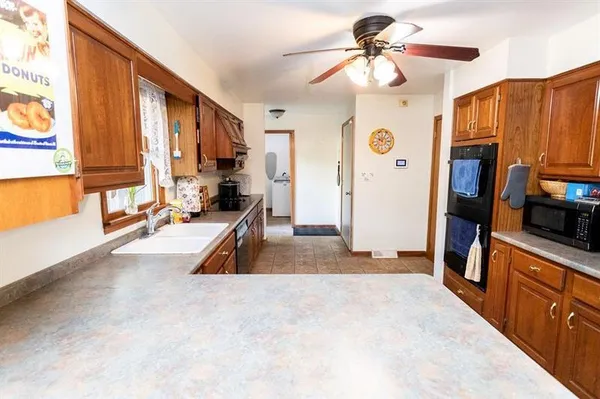 a view of a kitchen with kitchen island a large window cabinets a sink and stainless steel appliances