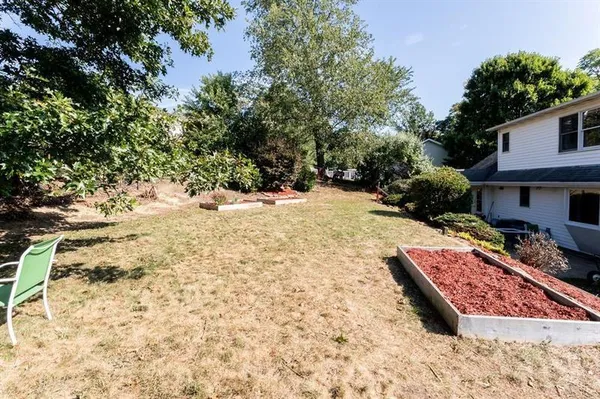 a view of a backyard with wooden fence and trees