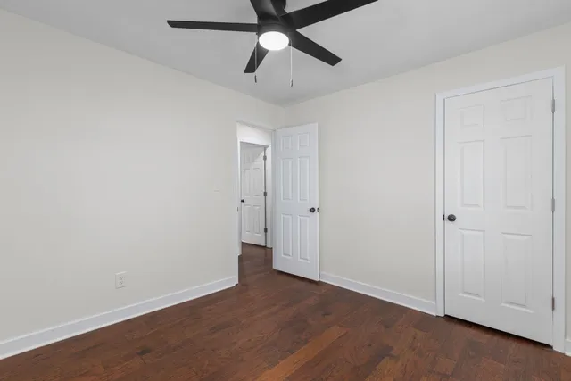 an empty room with wooden floor ceiling fan and windows