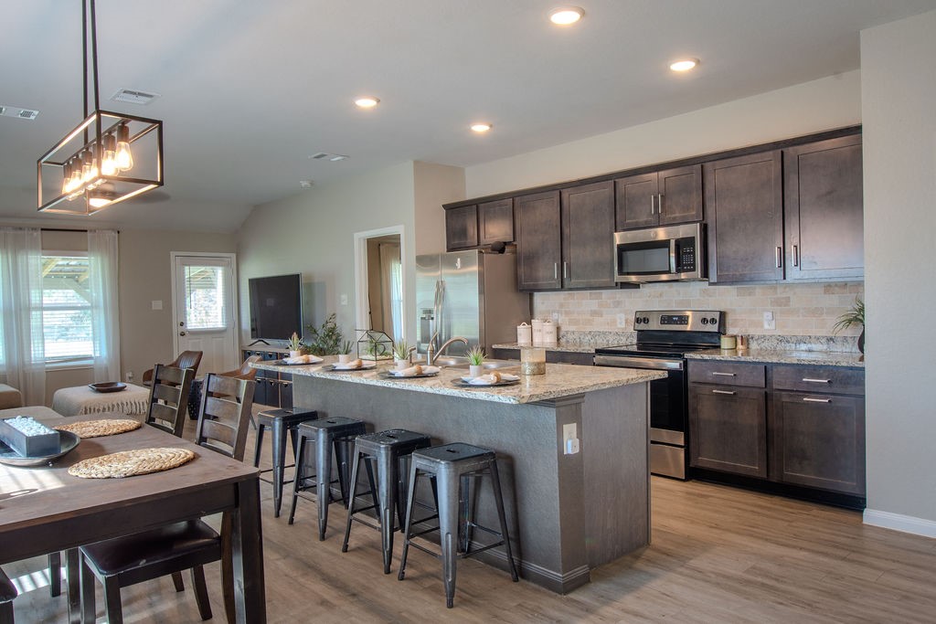 38340 Park View Drive Hempstead, TX 77445 - Photo 6 of 25 a kitchen with stainless steel appliances granite countertop a stove top oven a sink dishwasher a dining table and chairs