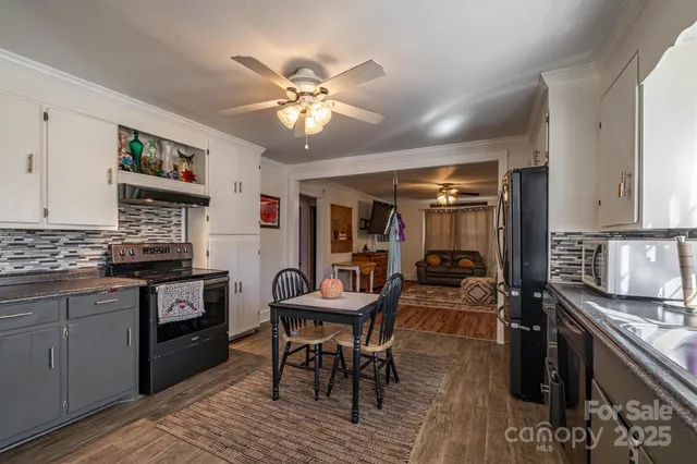 a kitchen with stainless steel appliances kitchen island granite countertop a stove top oven a sink a dining table and chairs with wooden floor