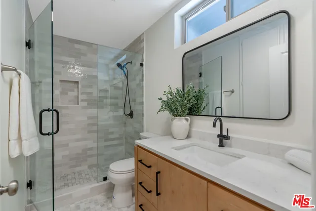 a bathroom with a granite countertop sink a toilet and shower