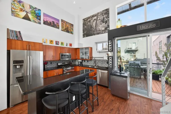 a kitchen with stainless steel appliances a refrigerator a stove top oven and a dining table with wooden floor