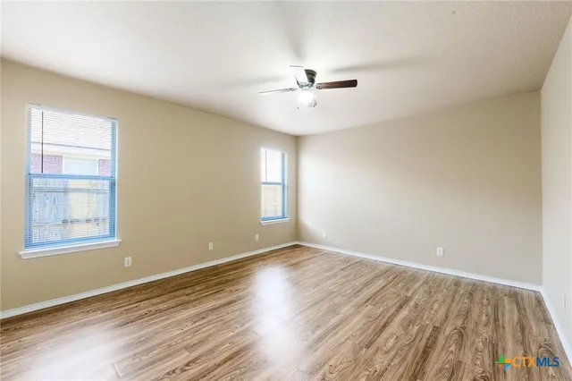 a view of an empty room with wooden floor and a window
