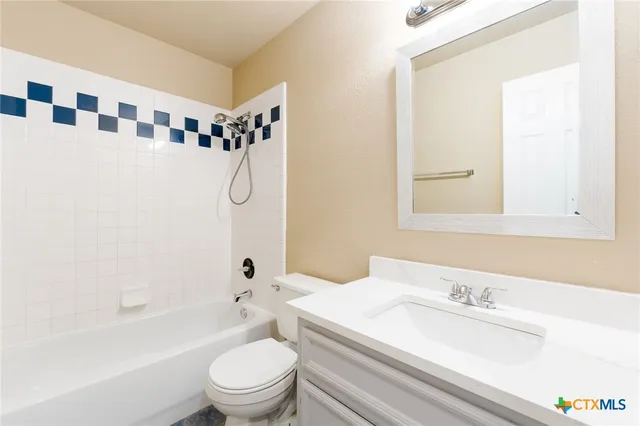 a bathroom with a granite countertop sink mirror vanity and toilet
