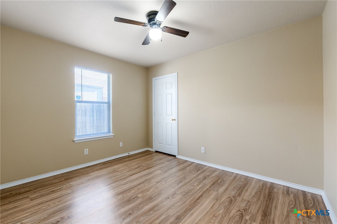 4701 Neta Drive Killeen, TX 76549 - Photo 21 of 28 an empty room with wooden floor ceiling fan and windows