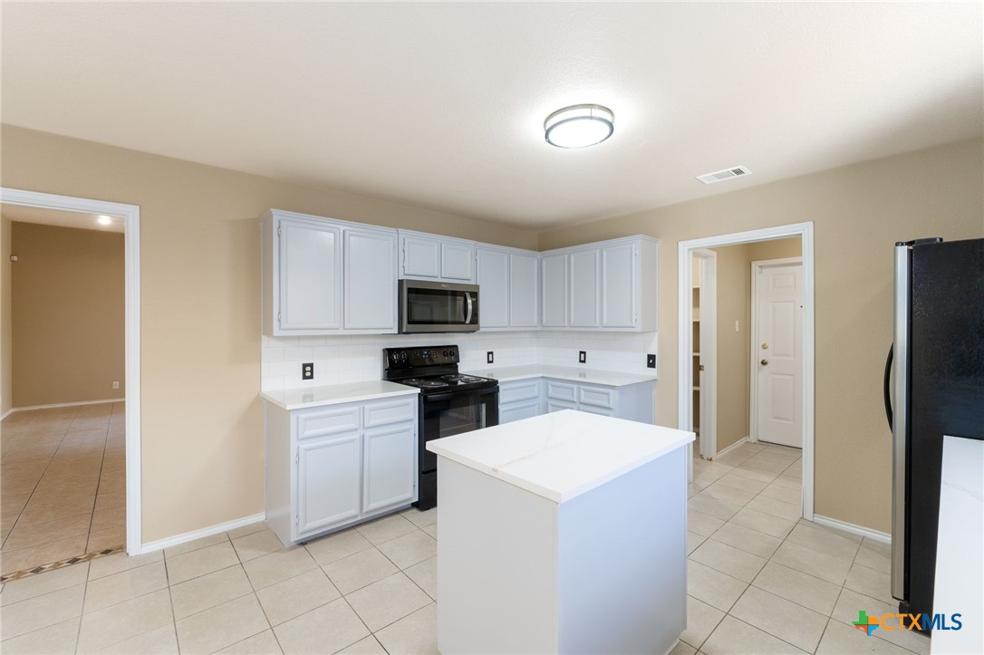 4701 Neta Drive Killeen, TX 76549 - Photo 10 of 28 a kitchen with a refrigerator a stove top oven and white cabinets