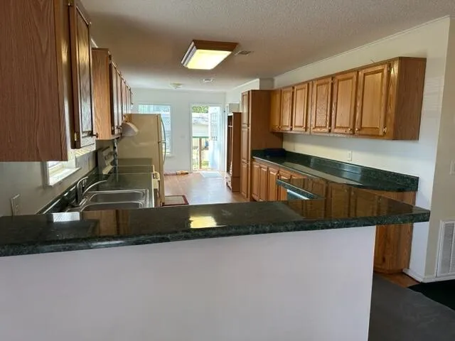 a kitchen with kitchen island granite countertop a sink a stove and a wooden cabinets