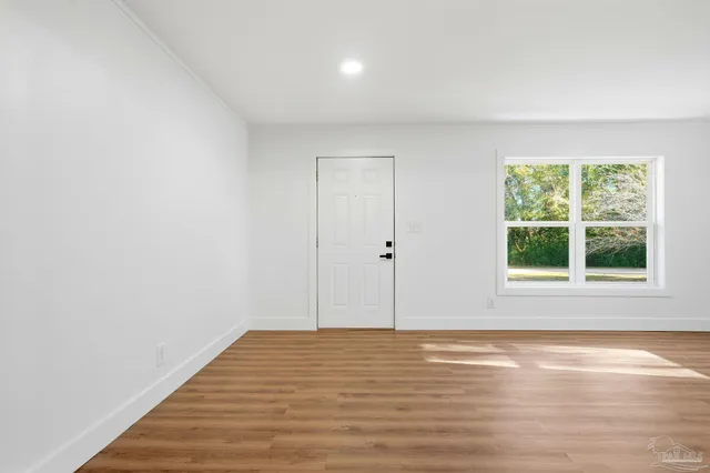 a view of an empty room with wooden floor and a window