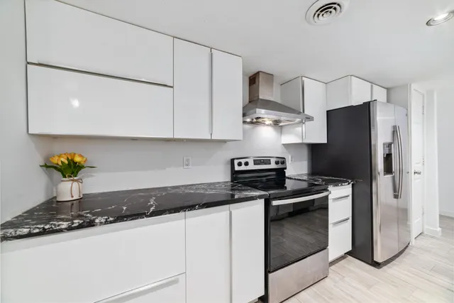 a kitchen with stainless steel appliances granite countertop a refrigerator a stove and a sink