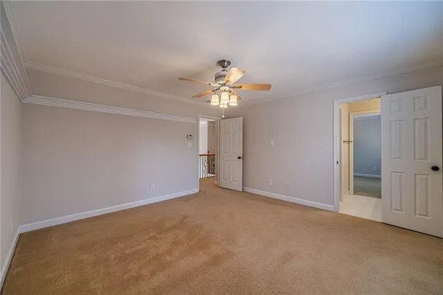 a view of a white house in front of a big yard with plants and large trees