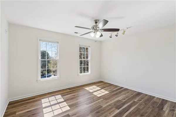 a view of empty room with wooden floor and fan