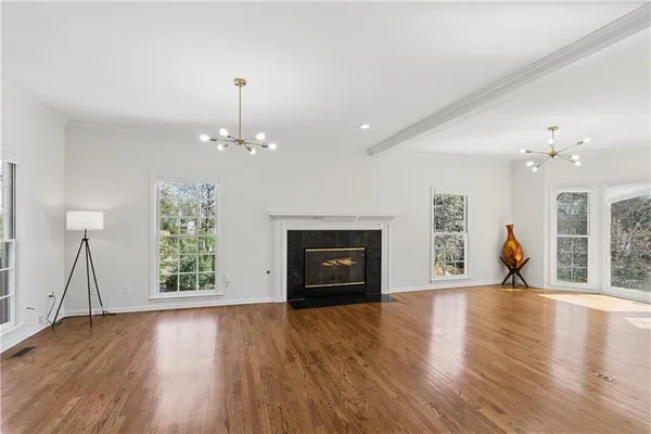 an empty room with wooden floor fireplace and windows