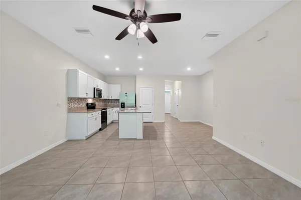 a view of an empty room with wooden floor and a ceiling fan
