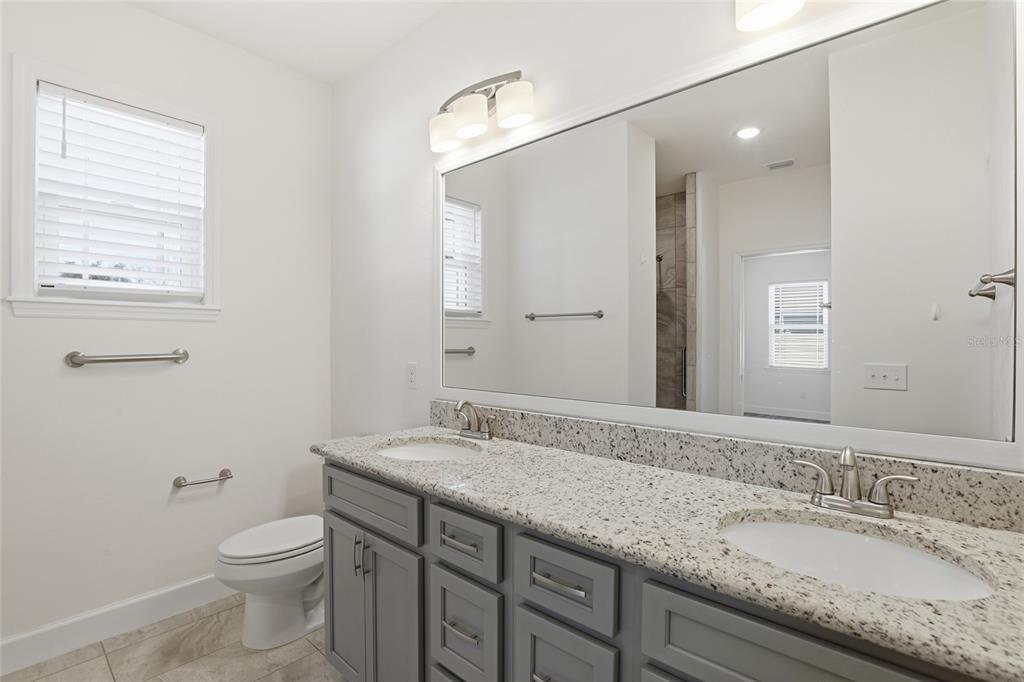 24302 Southwest 18th Road Newberry, FL 32669 - Photo 20 of 30 a bathroom with a granite countertop toilet a sink and a mirror