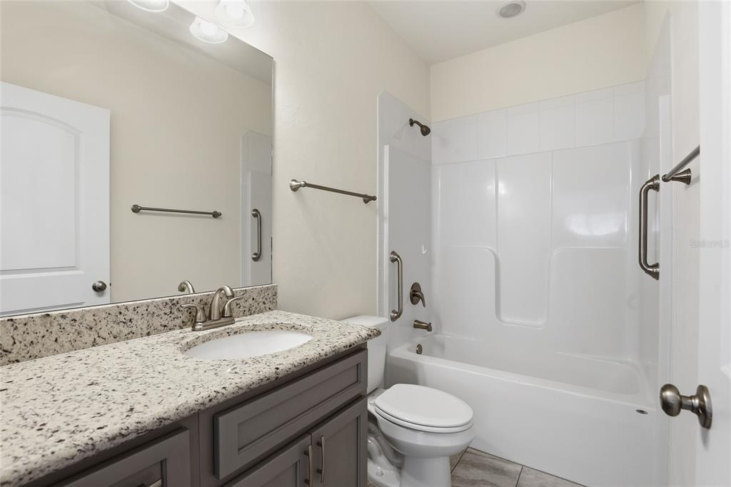 24302 Southwest 18th Road Newberry, FL 32669 - Photo 21 of 30 a bathroom with a granite countertop sink toilet and shower