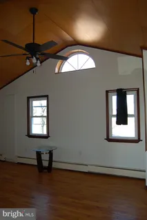 an empty room with wooden floor fan and windows