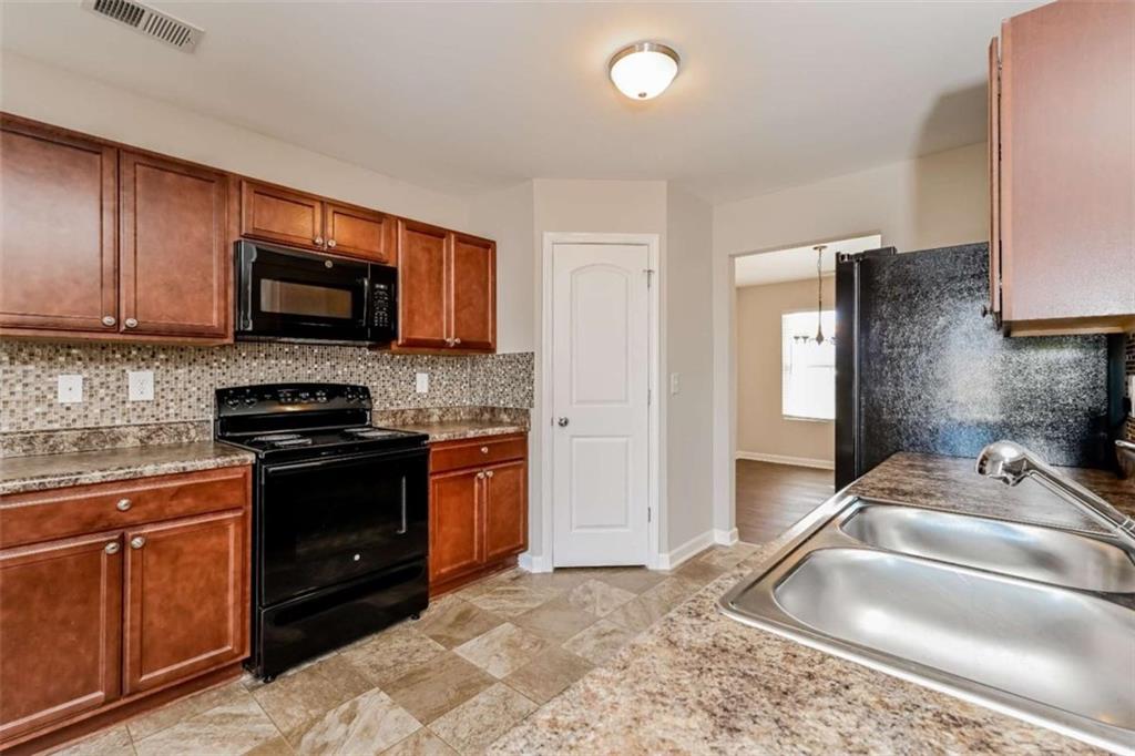 40 Tuesday Court Covington, GA 30016 - Photo 11 of 20 a kitchen with granite countertop a sink stove and microwave