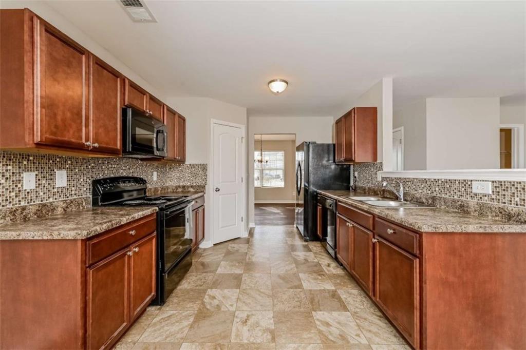 40 Tuesday Court Covington, GA 30016 - Photo 12 of 20 a large kitchen with stainless steel appliances granite countertop a stove a sink dishwasher a microwave oven and a refrigerator