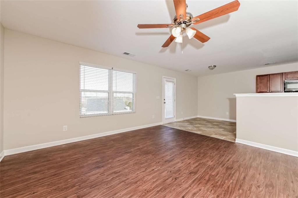 40 Tuesday Court Covington, GA 30016 - Photo 10 of 20 an empty room with wooden floor chandelier fan and windows