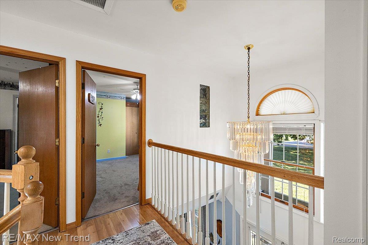 1450 Lenox Road Bloomfield Hills, MI 48304 - Photo 50 of 79 Hardwood flooring, white wall paint, crystal chandelier, arched transom window, and white balusters