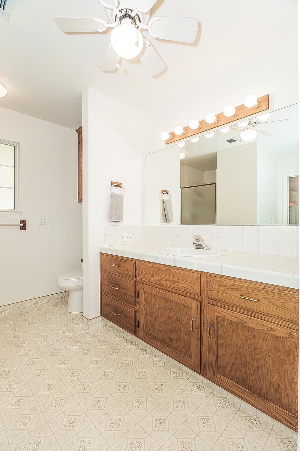 1415 West Riverglen Avenue Reedley, CA 93654 - Photo 17 of 48 a spacious bathroom with a granite countertop sink and a mirror